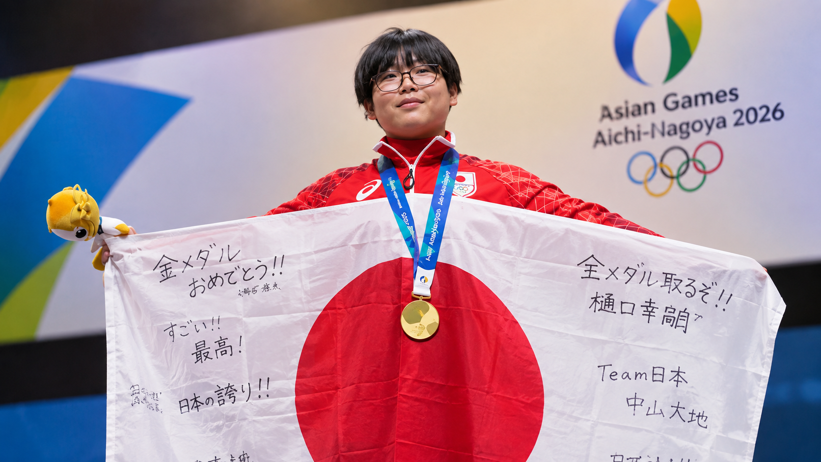 Young Japanese esports player holding a signed Japanese flag and wearing a gold medal at the 2026 Asian Games.