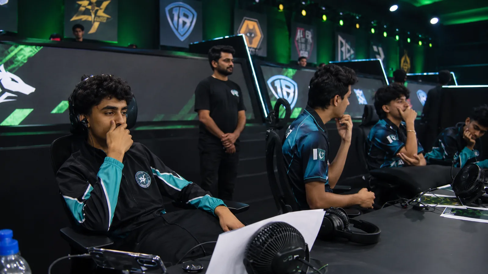 Pakistani esports players in teal-and-black jerseys sit at their stations during a PUBG Mobile esports tournament.