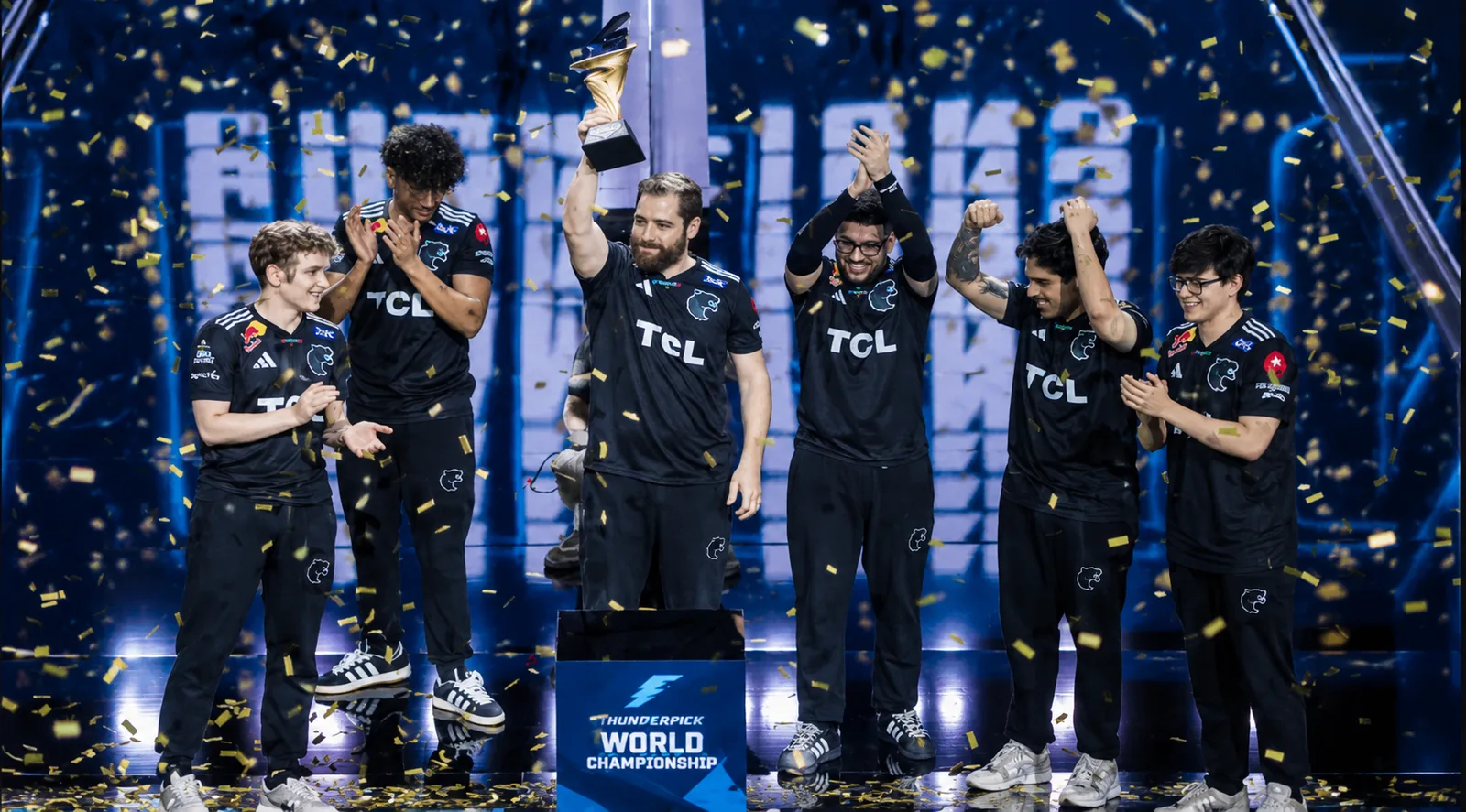 FURIA players celebrate their Thunderpick World Championship 2026 victory on stage, lifting the trophy amid golden confetti.